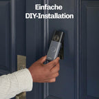 Person hält die HESLER Videotürklingel während der Montage an einer blauen Haustür, Hinweis auf einfache DIY-Installation.