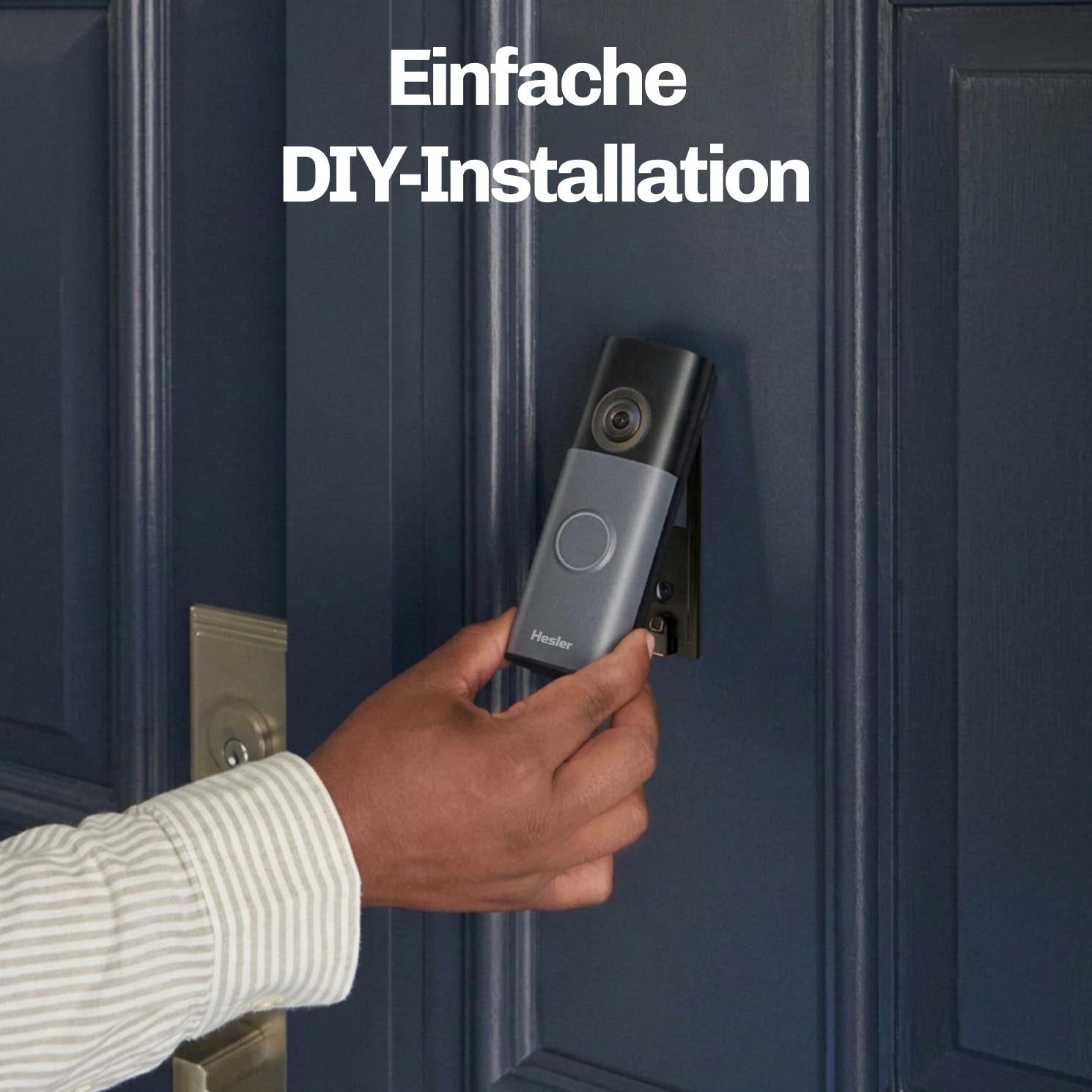 Person hält die HESLER Videotürklingel während der Montage an einer blauen Haustür, Hinweis auf einfache DIY-Installation.