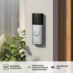 HESLER Videotürklingel an heller Hauswand neben Eingangstür montiert, mit Hinweisen zu 2K-Aufloesung, Nachtsicht und Schnellwechsel-Akku.